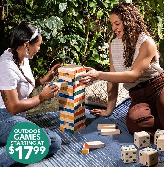 People playing outdoor games on a large outdoor rug. Outdoor games starting at $17.99.